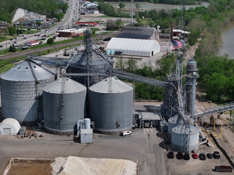 Aerial view of large industrial grain silos and storage facility with an American flag near a river and roadway in Aurora Indiana United States. Aerial view of large industrial grain silos and storage facility with an American flag near a river and roadway in Aurora Indiana United States.
