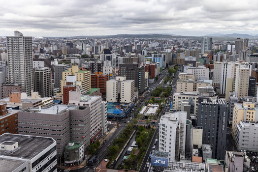 Aerial view of the dense urban cityscape of Sapporo with high rise buildings busy streets and infrastructure under a cloudy sky in Sapporo Hokkaido Japan. Aerial view of the dense urban cityscape of Sapporo with high rise buildings busy streets and infrastructure under a cloudy sky in Sapporo Hokkaido Japan.
