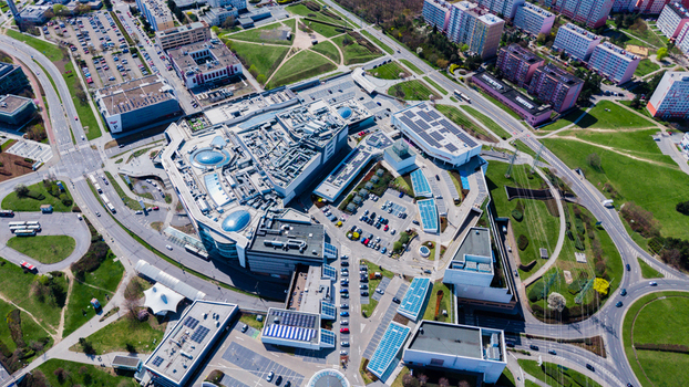Aerial view of a modern geometric building complex surrounded by vibrant green spaces and roads bustling with traffic Chodov Prague Czechia. Aerial view of a modern geometric building complex surrounded by vibrant green spaces and roads bustling with traffic Chodov Prague Czechia.