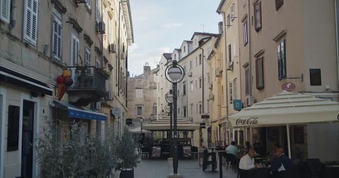 View of a narrow street with outdoor cafe seating in Croatia.
