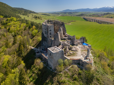 Aerial view of the medieval Castle Likava ruins situated on a forested hilltop overlooking green valleys and a distant highway bridge Likavka Zilina Region Slovakia. Aerial view of the medieval Castle Likava ruins situated on a forested hilltop overlooking green valleys and a distant highway bridge Likavka Zilina Region Slovakia.