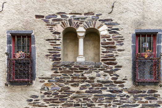 View of Eltz Castle featuring historic stone walls ornate wrought iron window grilles and a central arched niche with a stone pillar Wierschem Rhineland Palatinate Germany.
