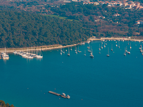 Aerial view of boats resting on the tranquil blue waters near a lush green coastline a serene harbor scene. Pula Istria County Croatia.