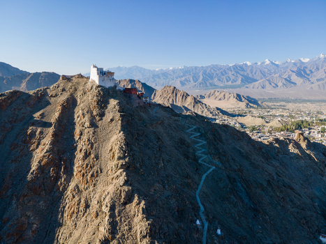 Aerial view of Leh Palace perched on a rocky mountain ridge with a winding path and panoramic views of the Himalayas in Leh Ladakh India. Aerial view of Leh Palace perched on a rocky mountain ridge with a winding path and panoramic views of the Himalayas in Leh Ladakh India.