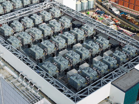 Aerial view of a data center rooftop featuring rows of industrial cooling units and HVAC systems in the United Kingdom. Aerial view of a data center rooftop featuring rows of industrial cooling units and HVAC systems in the United Kingdom.