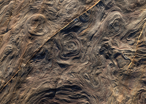 View of the intricate swirling patterns and eroded sandstone textures of the rocky coast Calafuria Toscana Italy.