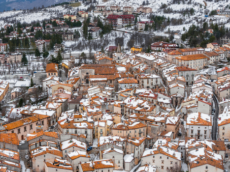 Aerial view of the historic town of Pescocostanzo featuring snow covered terracotta rooftops and stone architecture nestled in the mountains of Pescocostanzo Abruzzo Italy.