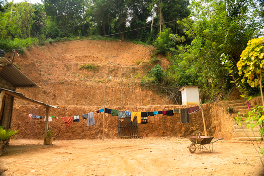 View of a terraced red earth embankment with laundry hanging on a line and a wheelbarrow in a rural yard Mirissa Southern Province Sri Lanka. View of a terraced red earth embankment with laundry hanging on a line and a wheelbarrow in a rural yard Mirissa Southern Province Sri Lanka.