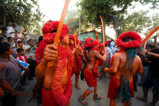 Munshiganj Bangladesh 13 April 2025 View of vibrantly painted performers adorned with striking red garlands and ceremonial swords engaging in a lively cultural procession amidst an eager crowd. Munshiganj Bangladesh 13 April 2025 View of vibrantly painted performers adorned with striking red garlands and ceremonial swords engaging in a lively cultural procession amidst an eager crowd.
