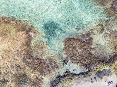 Aerial view of Kahalu u Beach Park featuring turquoise waters rocky reefs and people snorkeling and swimming in Kailua Kona Hawaii United States. Aerial view of Kahalu u Beach Park featuring turquoise waters rocky reefs and people snorkeling and swimming in Kailua Kona Hawaii United States.