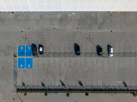 Aerial view of a parking lot featuring blue accessible parking spaces and several parked cars on a concrete surface in Opole Opole Voivodeship Poland. Aerial view of a parking lot featuring blue accessible parking spaces and several parked cars on a concrete surface in Opole Opole Voivodeship Poland.