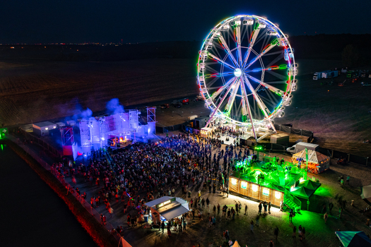 Herzogenaurach Germany 22 July 2022 Aerial view of the Open Beatz Festival featuring a large illuminated Ferris wheel and a crowded stage area at night. Herzogenaurach Germany 22 July 2022 Aerial view of the Open Beatz Festival featuring a large illuminated Ferris wheel and a crowded stage area at night.