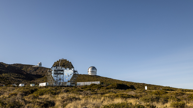 View of Roque de Los Muchachos Astrophysical Observatory with its distinctive telescope domes and hexagonal mirrors on a rocky hillside under a clear blue sky in Canarias Spain. View of Roque de Los Muchachos Astrophysical Observatory with its distinctive telescope domes and hexagonal mirrors on a rocky hillside under a clear blue sky in Canarias Spain.