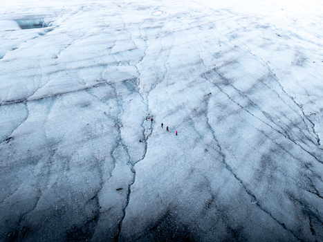 Aerial view of Breidamerkurjokull glacier with hikers walking across the icy surface and deep crevasses in Sveitarfelagid Hornafjordur Iceland. Aerial view of Breidamerkurjokull glacier with hikers walking across the icy surface and deep crevasses in Sveitarfelagid Hornafjordur Iceland.
