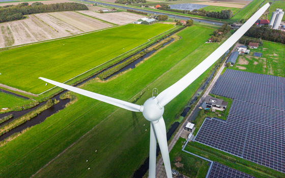Aerial view of a wind turbine standing next to a large solar panel field in the rural landscape of t Zand North Holland Netherlands. Aerial view of a wind turbine standing next to a large solar panel field in the rural landscape of t Zand North Holland Netherlands.