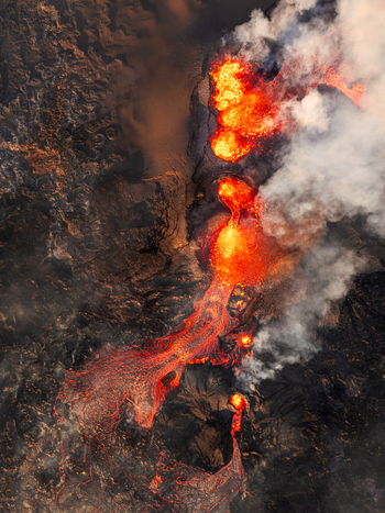 Aerial view of molten lava flowing from a volcanic eruption creating glowing rivers of fire across the dark basaltic landscape of Iceland. Aerial view of molten lava flowing from a volcanic eruption creating glowing rivers of fire across the dark basaltic landscape of Iceland.
