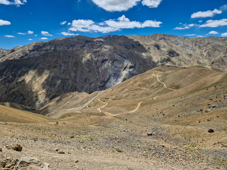 View of the winding Penzi La road traversing the rugged arid mountain landscape of Zanskar Ladakh India.