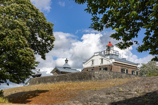 View of the historic Lichtwachterswoning Oud Kraggenburg with its lighthouse tower and stone walls under a cloudy sky in Kraggenburg Flevoland Netherlands. View of the historic Lichtwachterswoning Oud Kraggenburg with its lighthouse tower and stone walls under a cloudy sky in Kraggenburg Flevoland Netherlands.