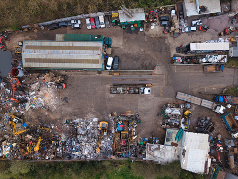 Aerial view of a scrap yard with vehicles and metal debris contrasting against the surrounding greenery Common Road Stafford England United Kingdom. Aerial view of a scrap yard with vehicles and metal debris contrasting against the surrounding greenery Common Road Stafford England United Kingdom.