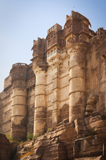 View of Mehrangarh Fort featuring intricate Rajput architecture and massive sandstone walls rising above rocky terrain in Jodhpur Rajasthan India. View of Mehrangarh Fort featuring intricate Rajput architecture and massive sandstone walls rising above rocky terrain in Jodhpur Rajasthan India.