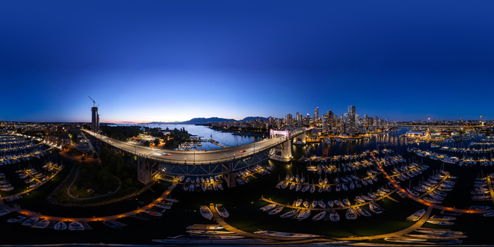 Aerial view of Burrard Street Bridge and illuminated Vancouver skyline at twilight featuring a marina with boats in False Creek Metro Vancouver A British Columbia Canada.