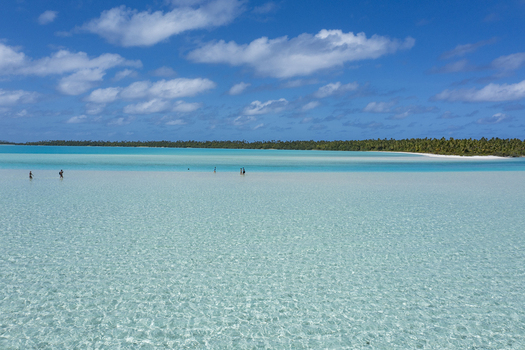 Aerial view of the shallow turquoise lagoon at One Foot Island in Aitutaki with clear water sandy bottom and people wading in the distance Arutanga Cook Islands. Aerial view of the shallow turquoise lagoon at One Foot Island in Aitutaki with clear water sandy bottom and people wading in the distance Arutanga Cook Islands.