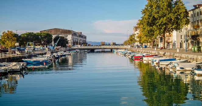 Rijeka Croatia 19 September 2026 View of a canal lined with small boats and yachts with historic buildings and trees along the waterfront under a clear blue sky. Rijeka Croatia 19 September 2026 View of a canal lined with small boats and yachts with historic buildings and trees along the waterfront under a clear blue sky.