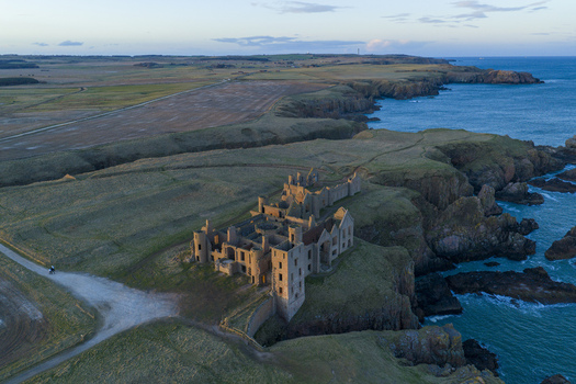 Aerial view of the historic ruins of Slains Castle perched on rugged cliffs overlooking the North Sea at sunset Cruden Bay Scotland United Kingdom. Aerial view of the historic ruins of Slains Castle perched on rugged cliffs overlooking the North Sea at sunset Cruden Bay Scotland United Kingdom.