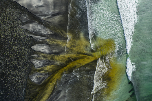 Aerial view of Talisker Bay Beach with dark volcanic sand and golden sediment flowing into turquoise waves Isle of Skye Scotland United Kingdom. Aerial view of Talisker Bay Beach with dark volcanic sand and golden sediment flowing into turquoise waves Isle of Skye Scotland United Kingdom.