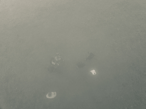 Aerial view of a landscape lost in thick grey green fog with faint dark and light shapes barely visible Obudu Cross River Nigeria.