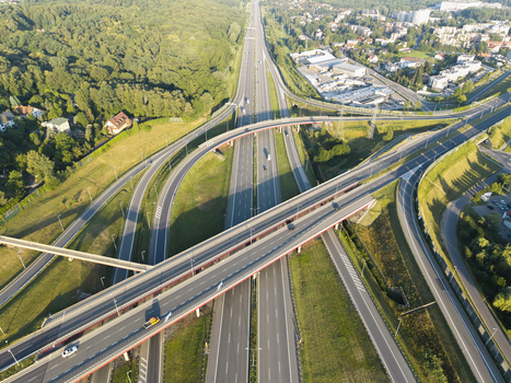 Aerial view of a modern highway interchange with multi level roads green grassy embankments and surrounding suburban landscape in Krakow Lesser Poland Voivode Poland.