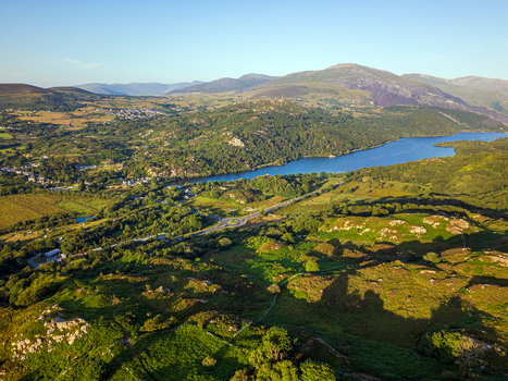 Aerial view of the village of Cwm y glo nestled beside Llyn Padarn surrounded by lush green hills and the rugged mountainous landscape of Snowdonia in Cwm y glo Wales United Kingdom. Aerial view of the village of Cwm y glo nestled beside Llyn Padarn surrounded by lush green hills and the rugged mountainous landscape of Snowdonia in Cwm y glo Wales United Kingdom.