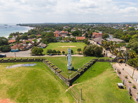 Aerial view of the historic star shaped Matara Fort and its white clock tower surrounded by green lawns and the coastal town in Matara Southern Province Sri Lanka. Aerial view of the historic star shaped Matara Fort and its white clock tower surrounded by green lawns and the coastal town in Matara Southern Province Sri Lanka.