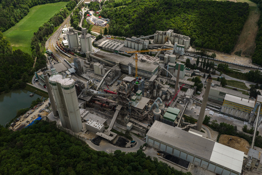 Aerial view of a large cement plant with tall silos industrial buildings and conveyor belts surrounded by lush green forests Mokra Horakov Jihomoravsky kraj Czechia. Aerial view of a large cement plant with tall silos industrial buildings and conveyor belts surrounded by lush green forests Mokra Horakov Jihomoravsky kraj Czechia.