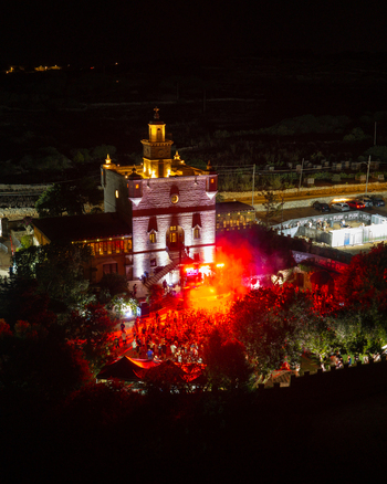 Mgarr Malta 17 September 2026 Aerial view of Castello Zamittello illuminated at night during an outdoor party with vibrant red lighting crowds of people and surrounding dark landscape. Mgarr Malta 17 September 2026 Aerial view of Castello Zamittello illuminated at night during an outdoor party with vibrant red lighting crowds of people and surrounding dark landscape.