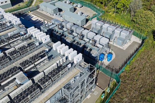 Aerial view of a data center facility featuring rows of industrial cooling units power transformers and electrical infrastructure in the United Kingdom.