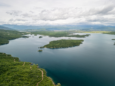 Aerial view of Slansko Lake with its islands surrounded by lush green hills under a cloudy sky in Niksic Municipality Montenegro. Aerial view of Slansko Lake with its islands surrounded by lush green hills under a cloudy sky in Niksic Municipality Montenegro.
