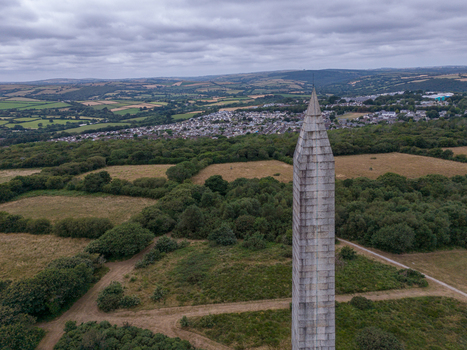 Aerial view of the stone Bodmin Monument rising above the surrounding fields and trees with the town of Bodmin in the background in Bodmin Cornwall United Kingdom. Aerial view of the stone Bodmin Monument rising above the surrounding fields and trees with the town of Bodmin in the background in Bodmin Cornwall United Kingdom.