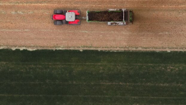 Aerial view of a red tractor with a trailer in a field Czechia.