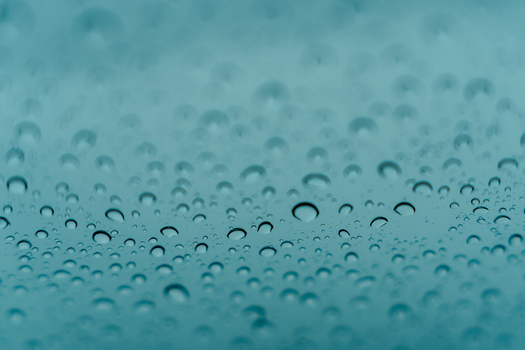View of water droplets on a glass surface with a soft blue background Iceland.