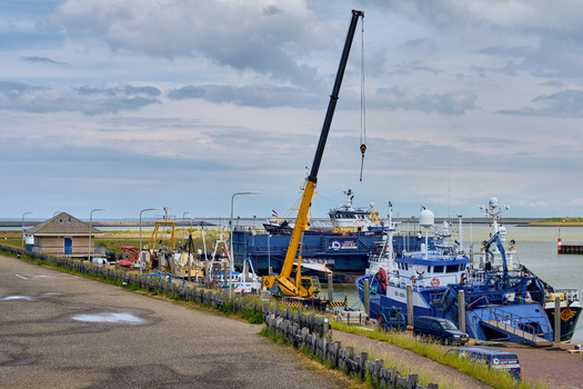 Den Oever Netherlands 18 May 2026 View of British fleet vessels being renovated at the Machinefabriek fishing repair wharf with a large yellow crane in the harbor.