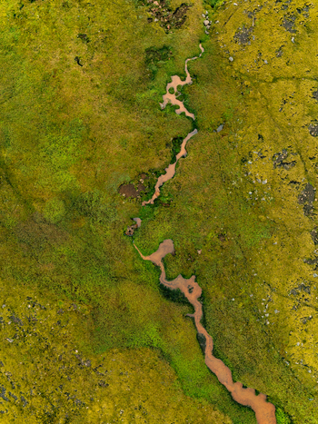 Aerial view of the winding river near Haifoss waterfall surrounded by vibrant green mossy terrain and rocky patches in Skeida og Gnupverjah Iceland. Aerial view of the winding river near Haifoss waterfall surrounded by vibrant green mossy terrain and rocky patches in Skeida og Gnupverjah Iceland.