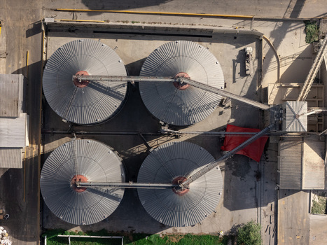 Aerial view of four large industrial grain silos with metal roofs and conveyor systems at a facility in Bajos de Haina San Cristobal Provinc Dominican Republic.