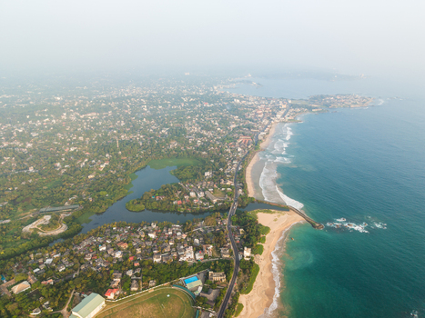Aerial view of the coastal landscape featuring sandy beaches a winding road and lush tropical greenery surrounding a calm lagoon in Galle Southern Province Sri Lanka.