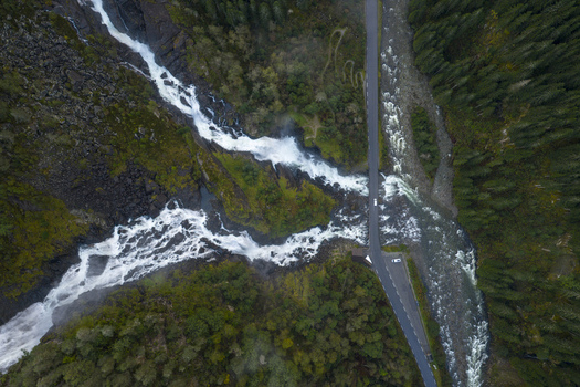 Aerial view of Latefossen waterfall cascading through lush green forests and under a stone bridge on the scenic road Skare Vestland Norway.