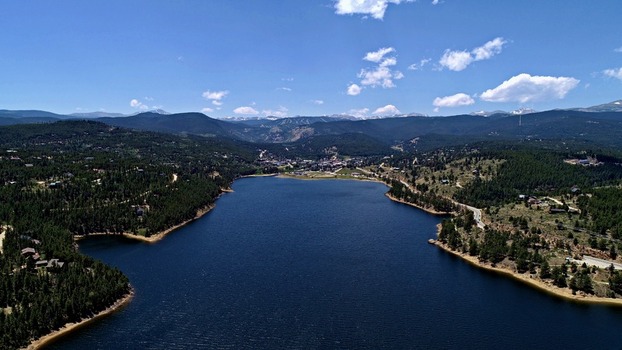 Aerial view of Barker Meadow Reservoir surrounded by dense pine forests and rolling mountains under a clear blue sky in Boulder County Colorado United States. Aerial view of Barker Meadow Reservoir surrounded by dense pine forests and rolling mountains under a clear blue sky in Boulder County Colorado United States.