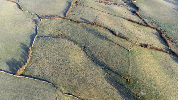 Aerial view of sun kissed fields divided by stone walls cast long shadows creating a tapestry of light and shadow over the undulating landscape England United Kingdom. Aerial view of sun kissed fields divided by stone walls cast long shadows creating a tapestry of light and shadow over the undulating landscape England United Kingdom.