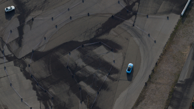 Aerial view of a light blue sports car driving on a paved track marked with cones and tire marks at the Hockenheimring in Hockenheim Baden Wurttemberg Germany. Aerial view of a light blue sports car driving on a paved track marked with cones and tire marks at the Hockenheimring in Hockenheim Baden Wurttemberg Germany.