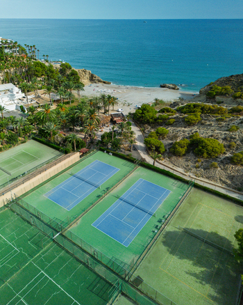 Aerial view of tennis courts located next to a sandy beach and the Mediterranean Sea in Spain.