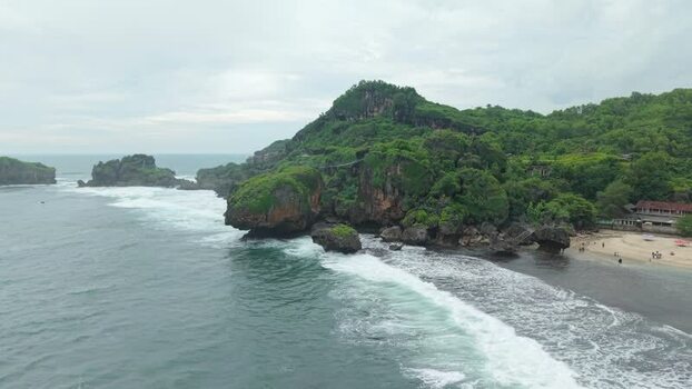 Aerial view of Siung Beach with rocky cliffs and waves Indonesia.